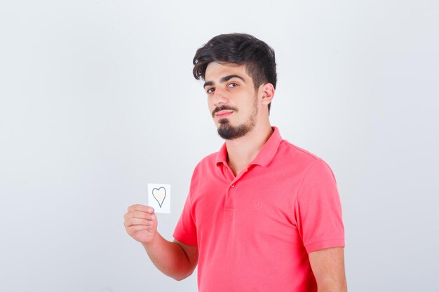 Young male holding sticky note while looking away in t-shirt and looking blissful. front view.