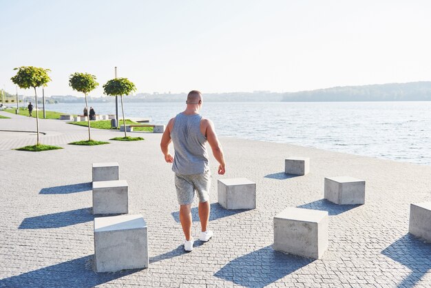 Young male jogger athlete training and doing workout outdoors in city.