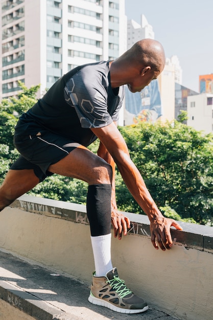 Young male jogger training and doing workout outdoors in city