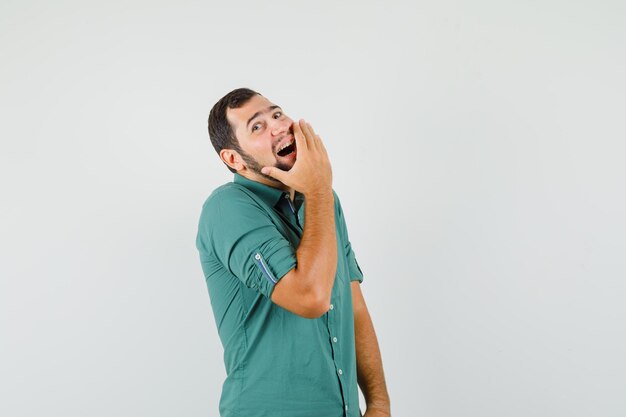 Young male laughing in green shirt and looking cute. front view.