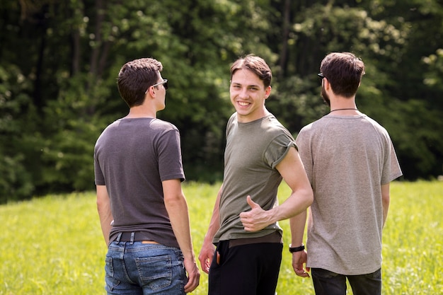 Free Photo young male making excellent sign with friends standing back in meadow