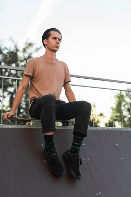 Young male model sitting on skateboard