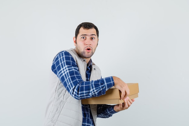 Young male opening box in shirt,jacket and looking excited. front view.