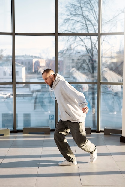 Young male performer dancing in a building with big windows