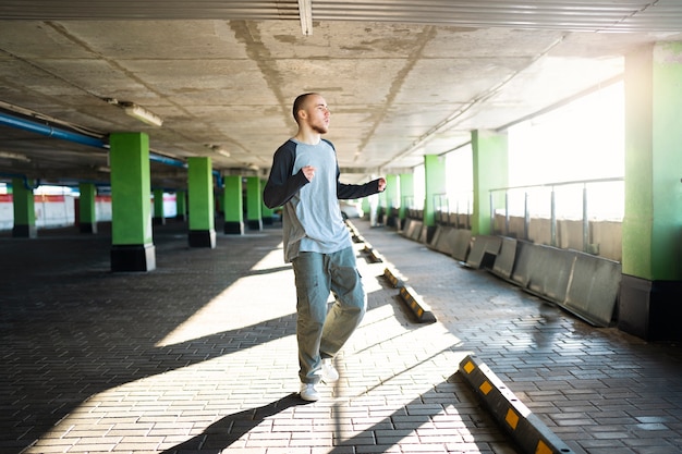 Free photo young male performer dancing in a parking lot with pilons