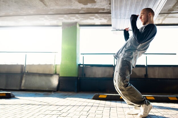 Free photo young male performer dancing in a parking lot with pilons