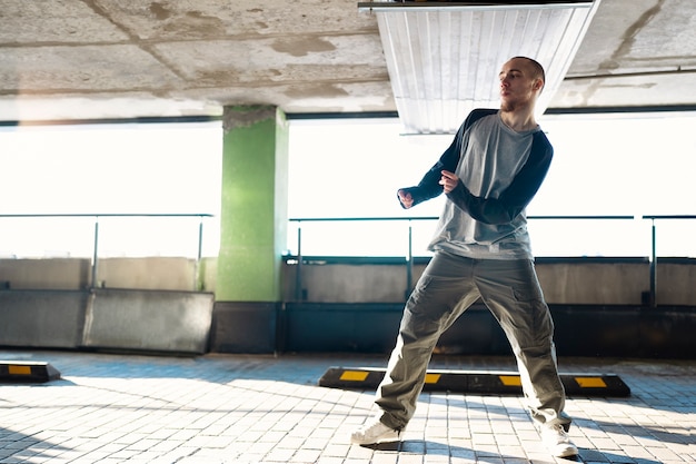 Free photo young male performer dancing in a parking lot with pilons