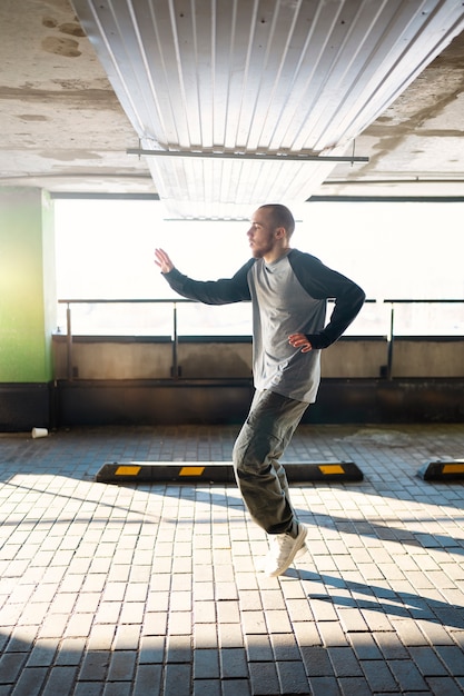 Free Photo young male performer dancing in a parking lot with pilons