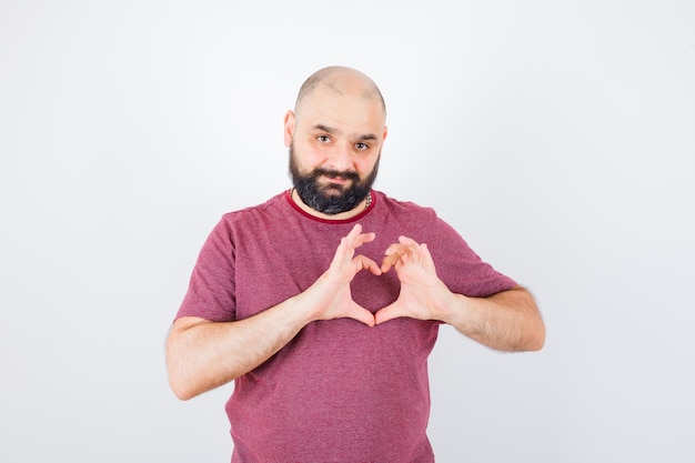 Free Photo young male in pink t-shirt showing peace gesture and looking beloved , front view.