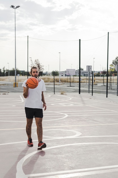 Young male player with basketball in court