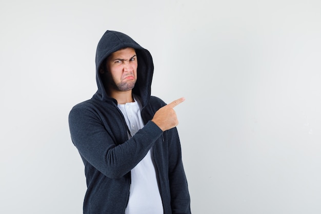 Free photo young male pointing to the right side in t-shirt, jacket and looking displeased. front view.