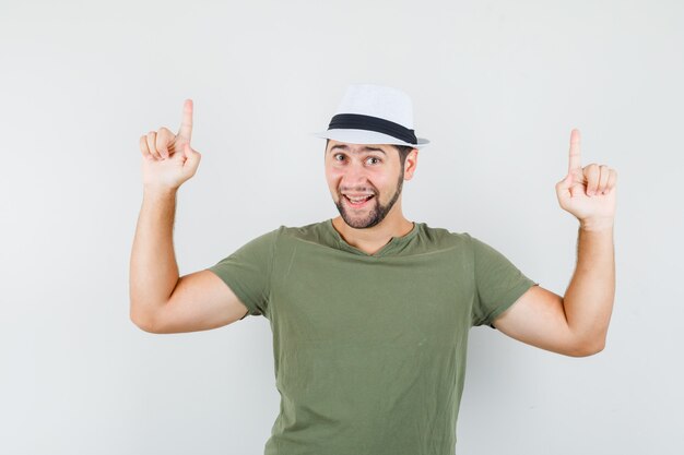 Young male pointing up in green t-shirt and hat and looking jolly