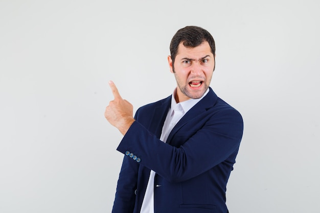 Young male pointing up in shirt, jacket and looking angry