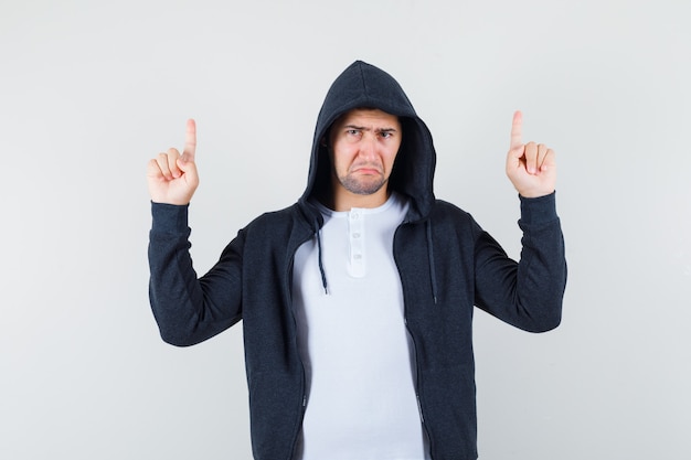 Free Photo young male pointing up in t-shirt, jacket and looking upset. front view.