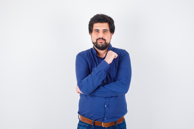 Young male posing while standing in blue shirt and looking confident. front view.