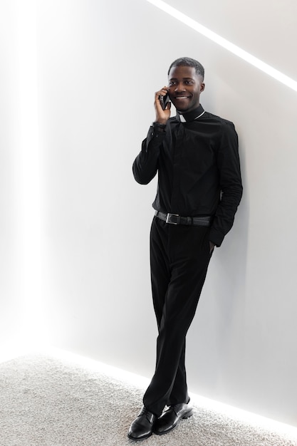 Free photo young male priest using a modern smartphone