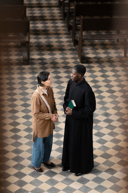 Free Photo young male priest and woman talking in the church while holding a bible