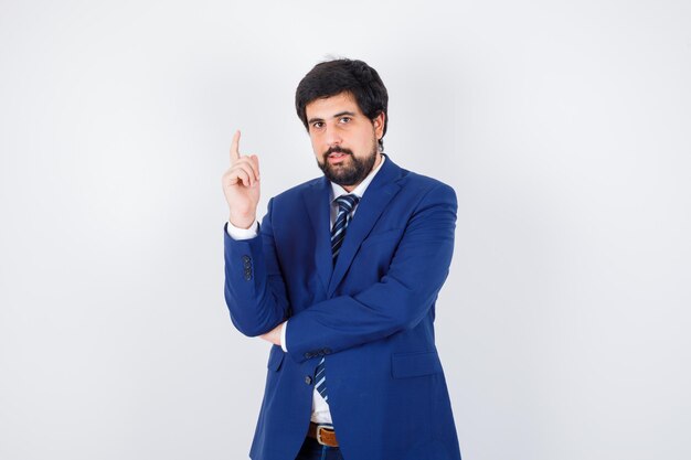 Young male in shirt,jacket,tie pointing up and looking serious , front view.