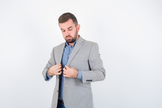 Free Photo young male in shirt, jeans, suit jacket holding lapels while posing and looking serious , front view.