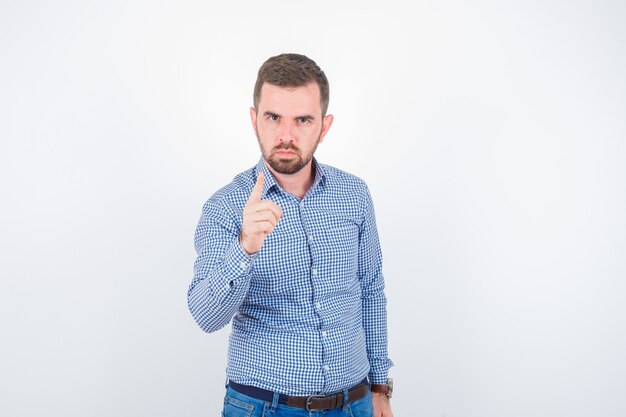 Young male in shirt threating with finger and looking serious , front view.