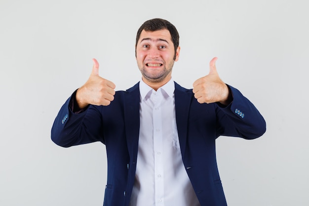 Free photo young male showing double thumbs up in shirt and jacket and looking happy