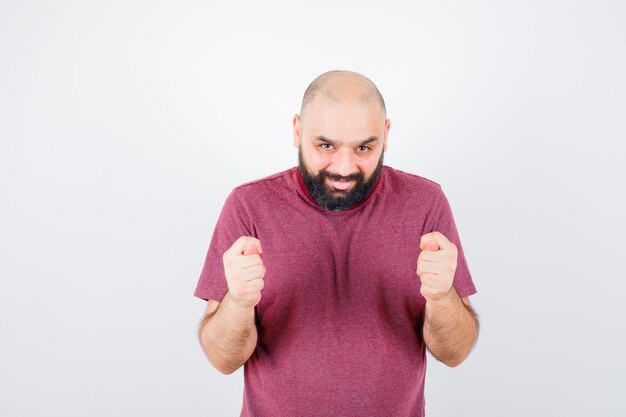 Young male showing fig gesture in pink t-shirt , front view.