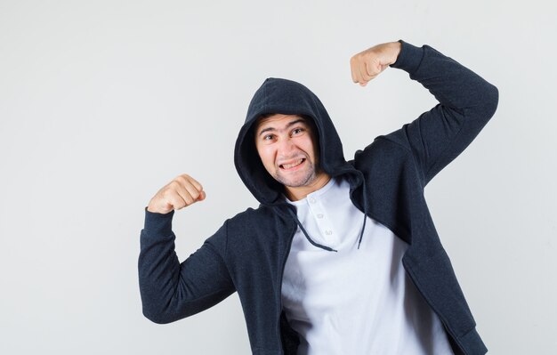 Young male showing muscles of arms in t-shirt, jacket and looking confident. front view.