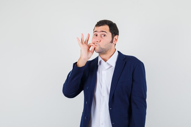 Young male showing zip gesture in shirt