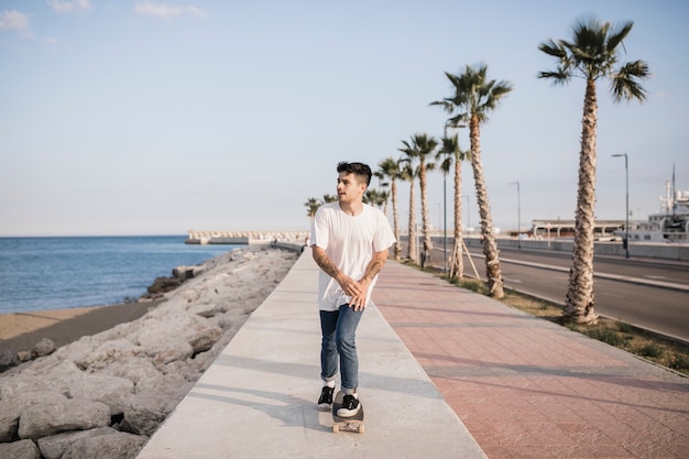 Young male skating on pavement with skateboard