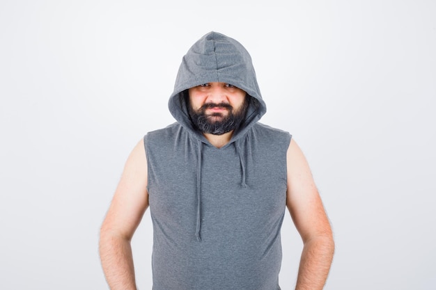 Free Photo young male in sleeveless hoodie, cap posing while standing and looking cute , front view.