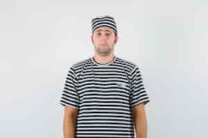 Free photo young male in t-shirt, hat looking at camera and looking scared , front view.