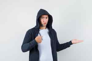 Free photo young male in t-shirt, jacket pointing at himself, spreading palm aside and looking confused , front view.