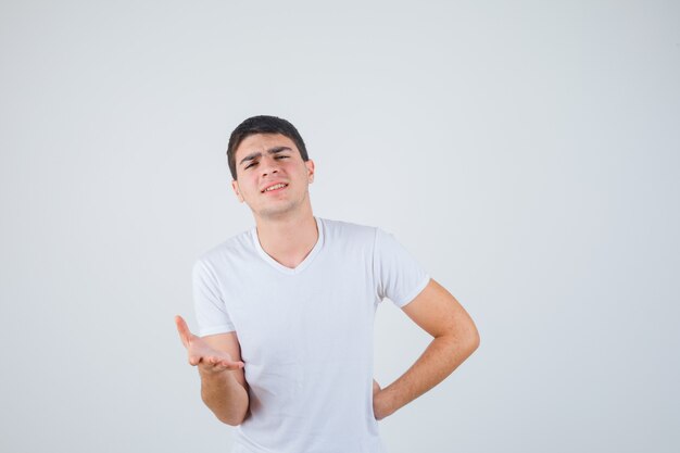 Young male in t-shirt stretching hand in questioning gesture and looking confident , front view.