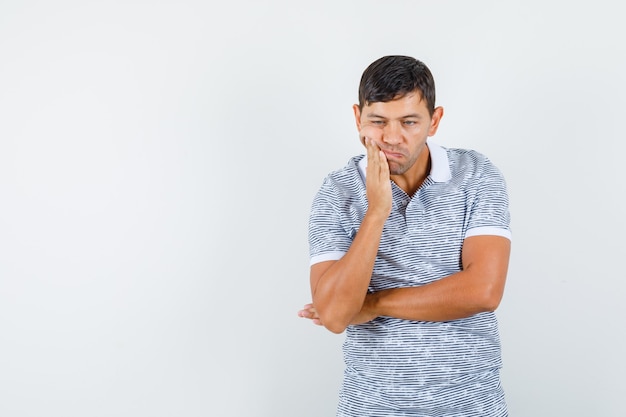 Young male in t-shirt suffering from toothache and looking upset