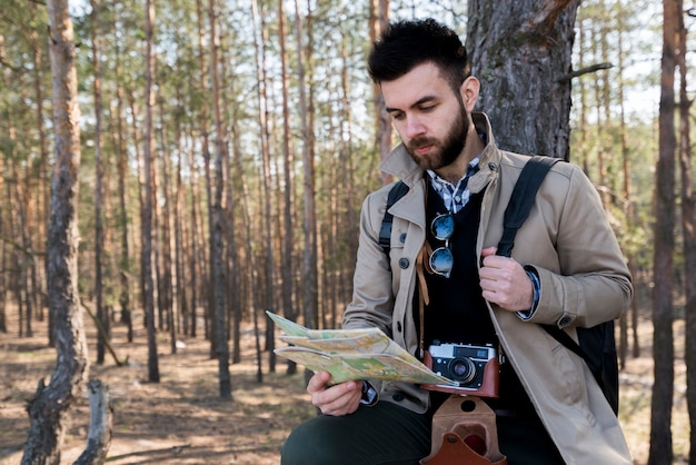 Free photo a young male tourist reading the map in the forest