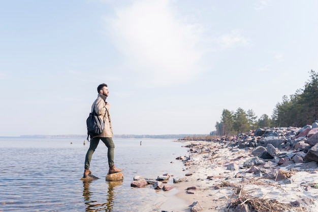 Young male traveler with is backpack looking at view