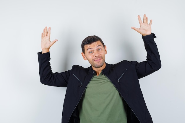 Free photo young male waving hands to say goodbye in t-shirt, jacket and looking cheerful. front view.