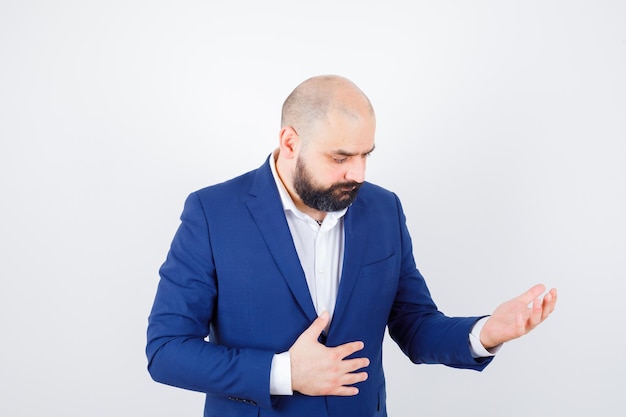 Free Photo young male in white shirt, jacket looking at his empty palm and looking sad , front view.