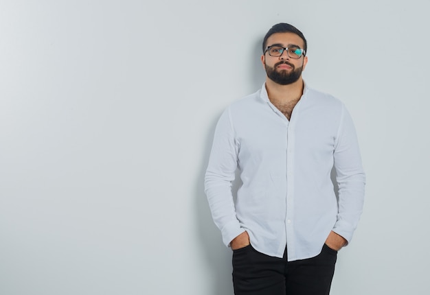 Free Photo young male in white shirt, pants holding hands in pockets and looking elegant