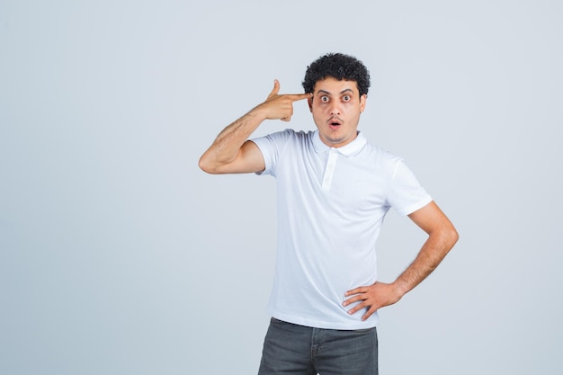 Young male in white t-shirt, pants making suicide gesture and looking surprised , front view.