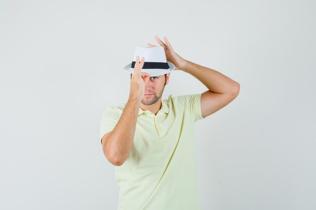 Young man adjusting his hat in t-shirt and looking confident  