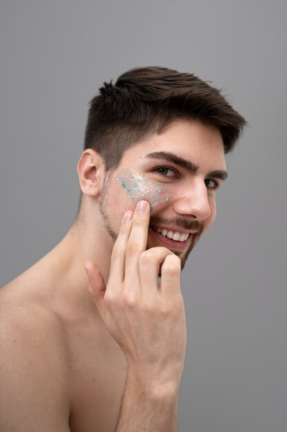 Young man applying shiny lotion on her face