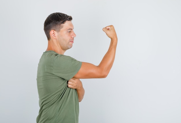 Free Photo young man in army green t-shirt showing muscle and looking strong .