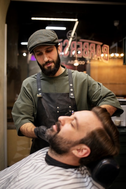 Young man at the barber's shop getting his beard trimmed