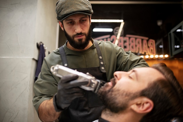 Free Photo young man at the barber's shop getting his beard trimmed