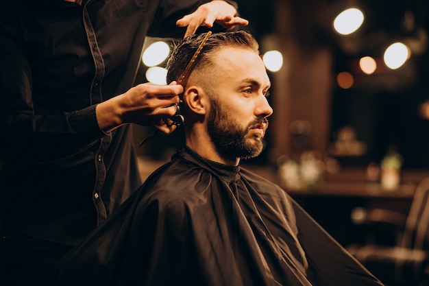 Free photo young man at barbershop trimming hair