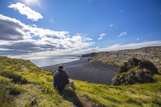 Young man on the beautiful stone beaches of the Snaefellsnes peninsula in a natural viewpoint