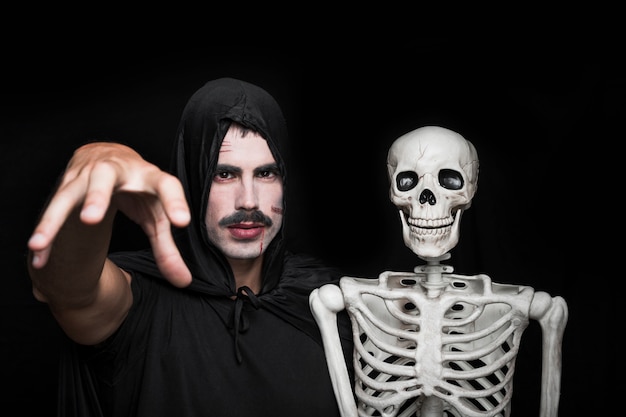 Young man in black clothes posing with skeleton