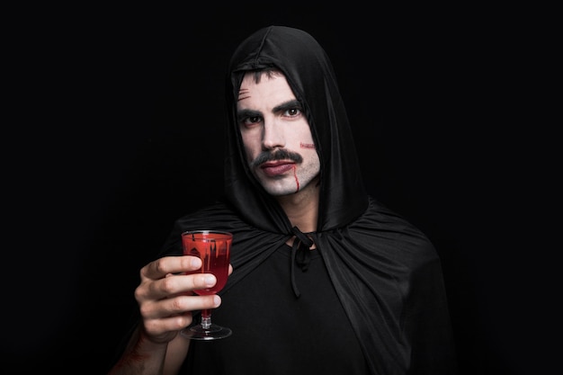 Young man in black costume posing in studio with glass