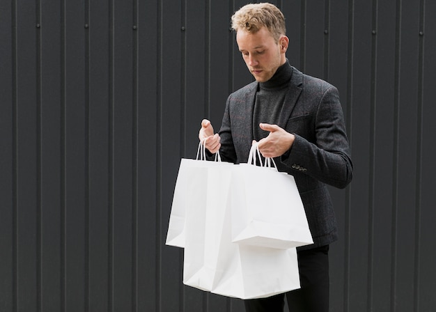 Free Photo young man in black looking in shopping bags